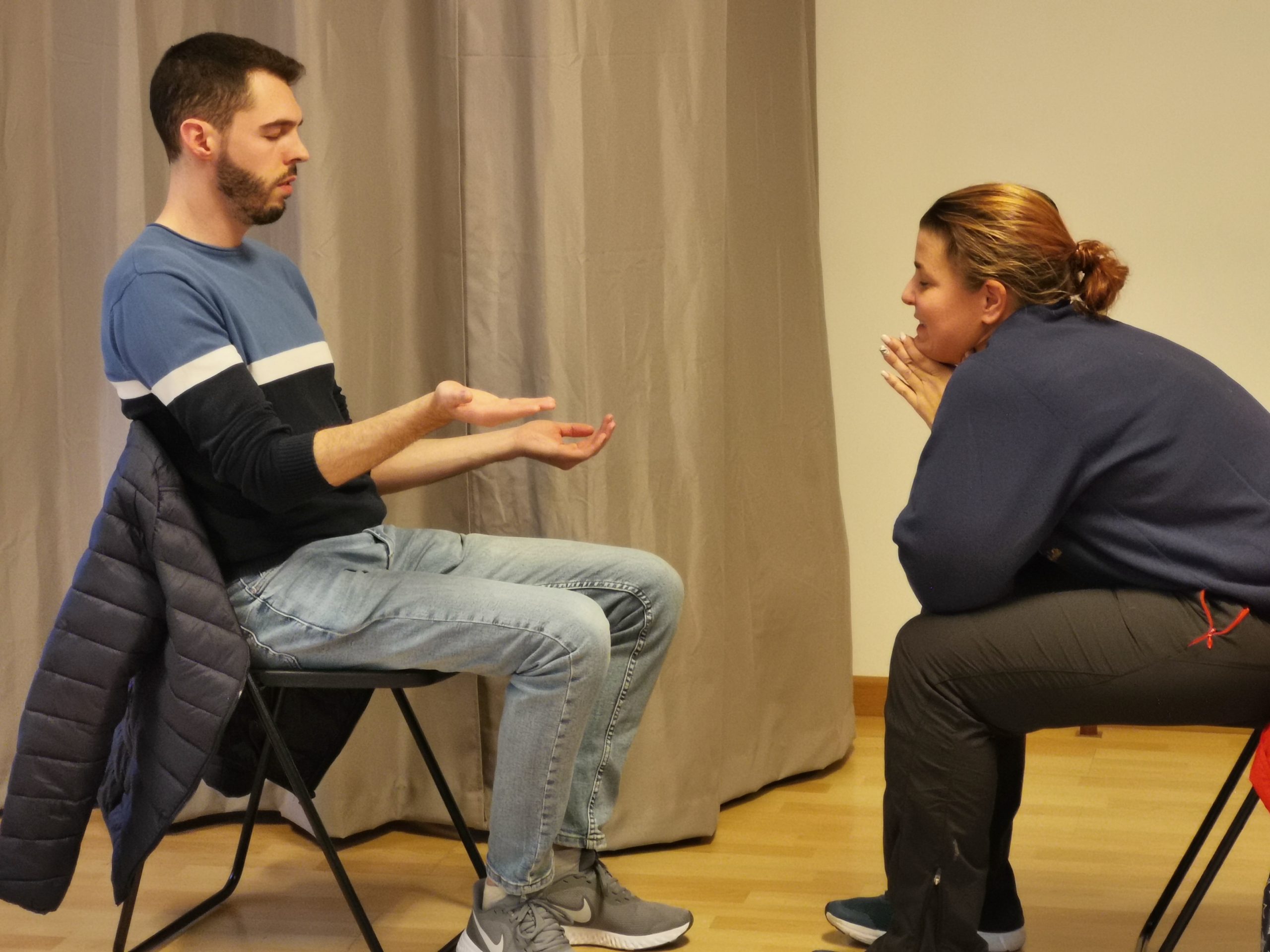 Pareja de alumnos del curso haciendo un ejercicio de hipnosis Pareja de alumnos del curso, sentado en una silla, haciendo un ejercicio de hipnosis con levitación de mano.